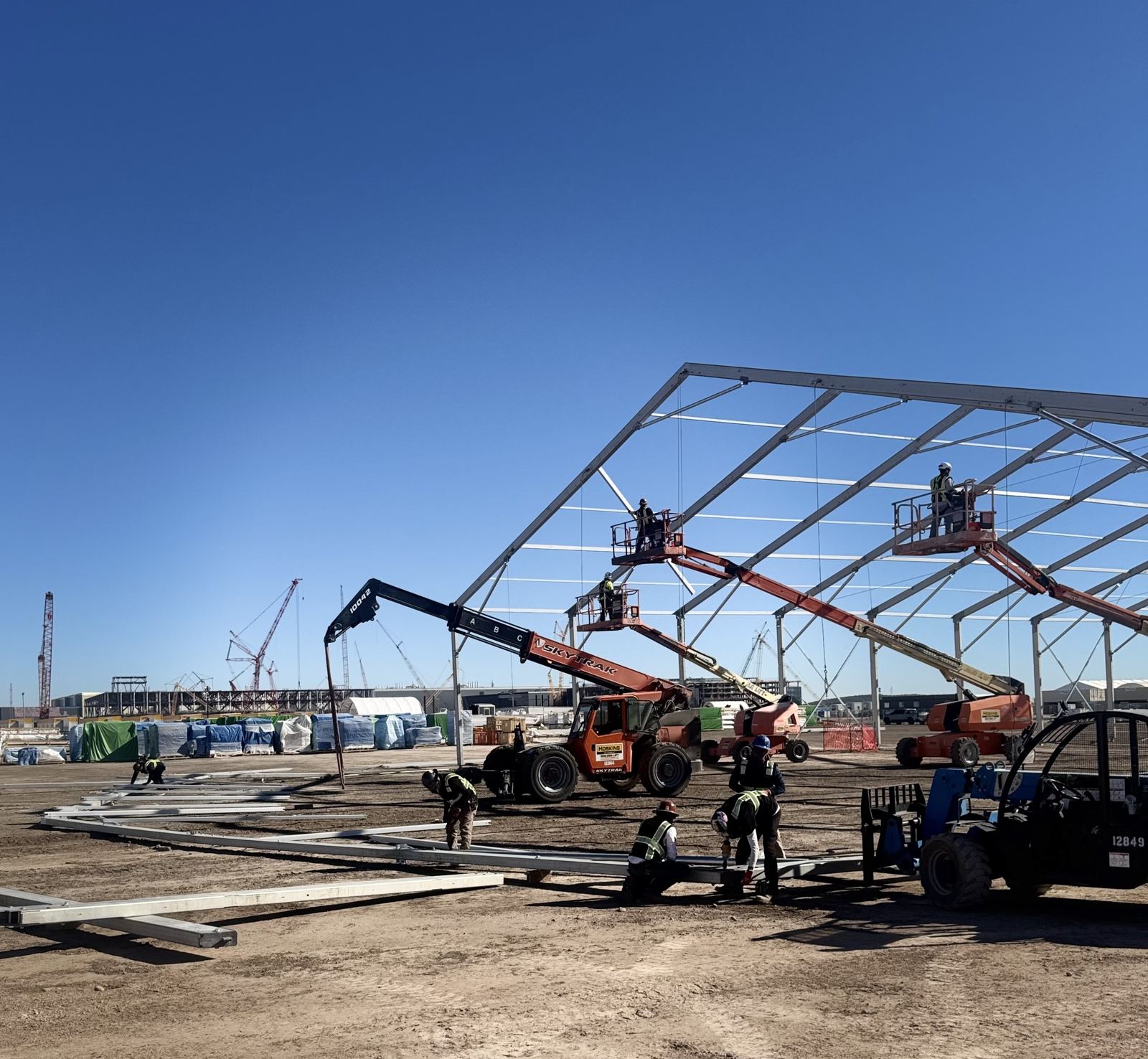 Crew and lifts installing a large structure frame